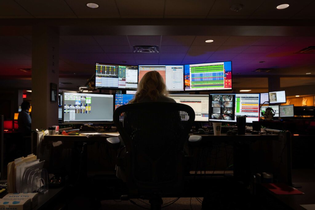 A police dispatcher monitors a collection of screens.